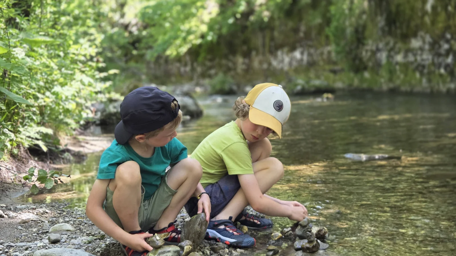 Nos deux garçons accroupis au bord d'un ruisseau, occupés à empiler des galets ensemble.