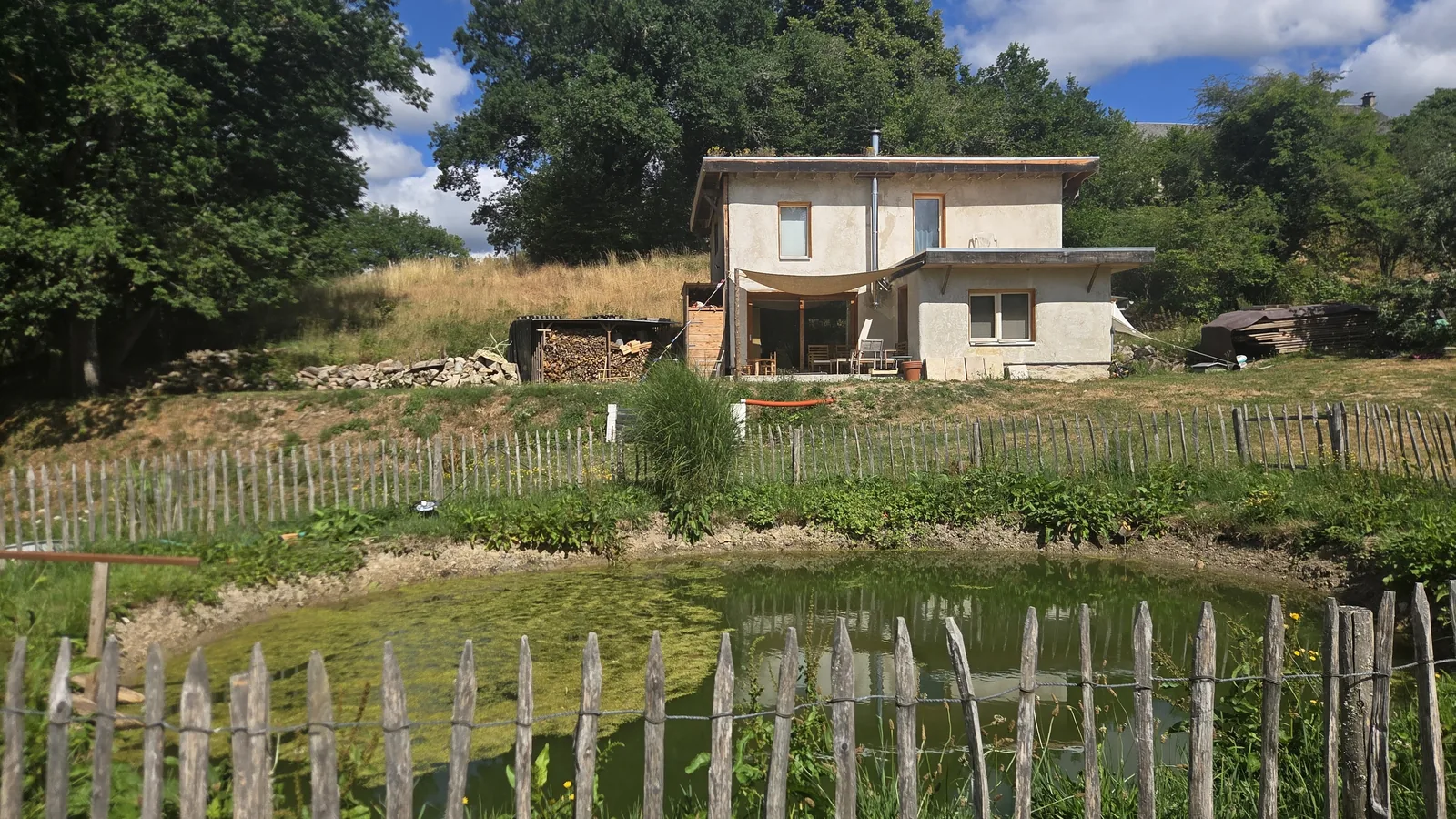La maison au-dessus du bassin, le potager clôturé au premier plan