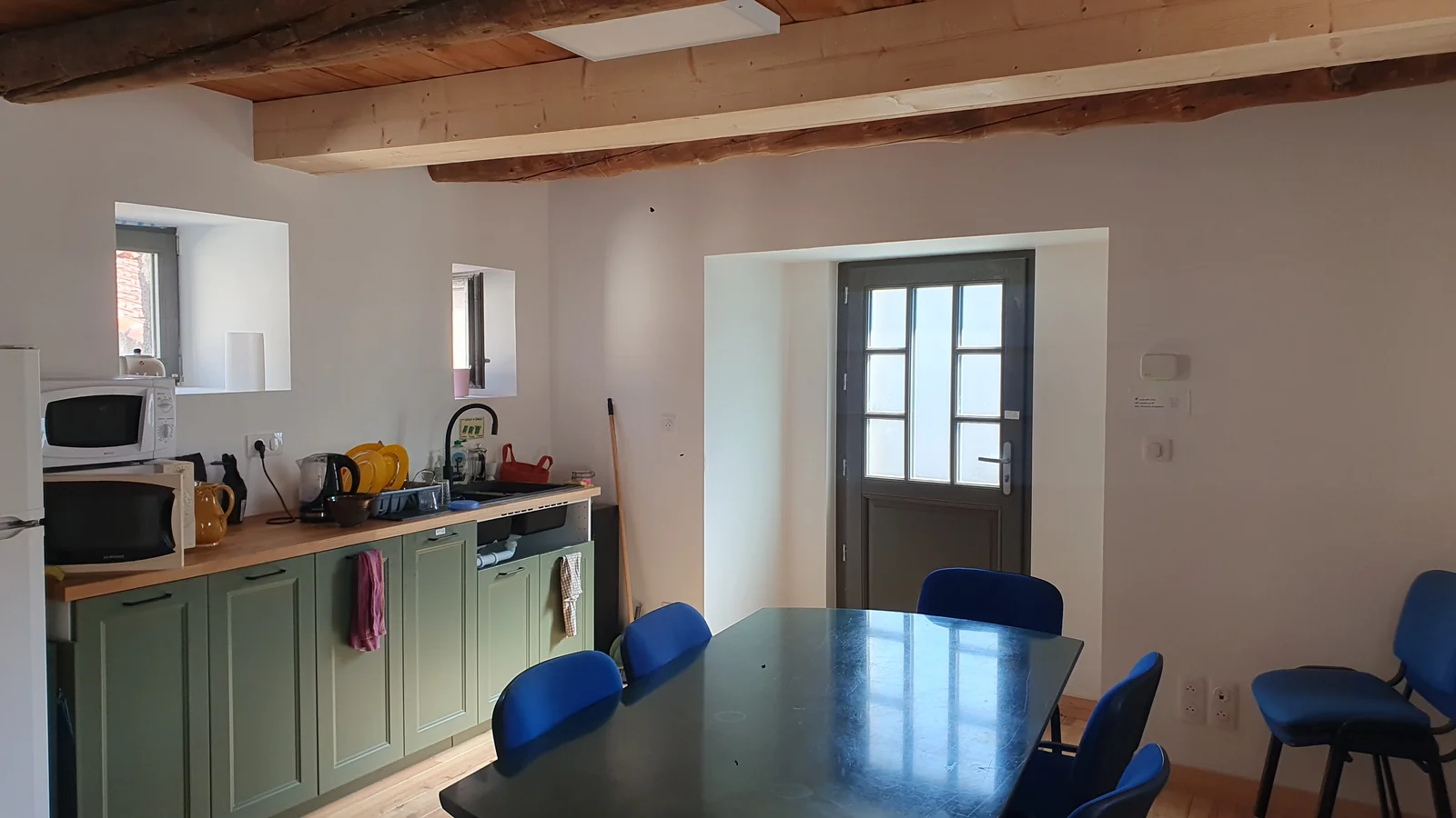 L'espace cuisine et salle de réunion commun de l'étage, meubles verts et grande table