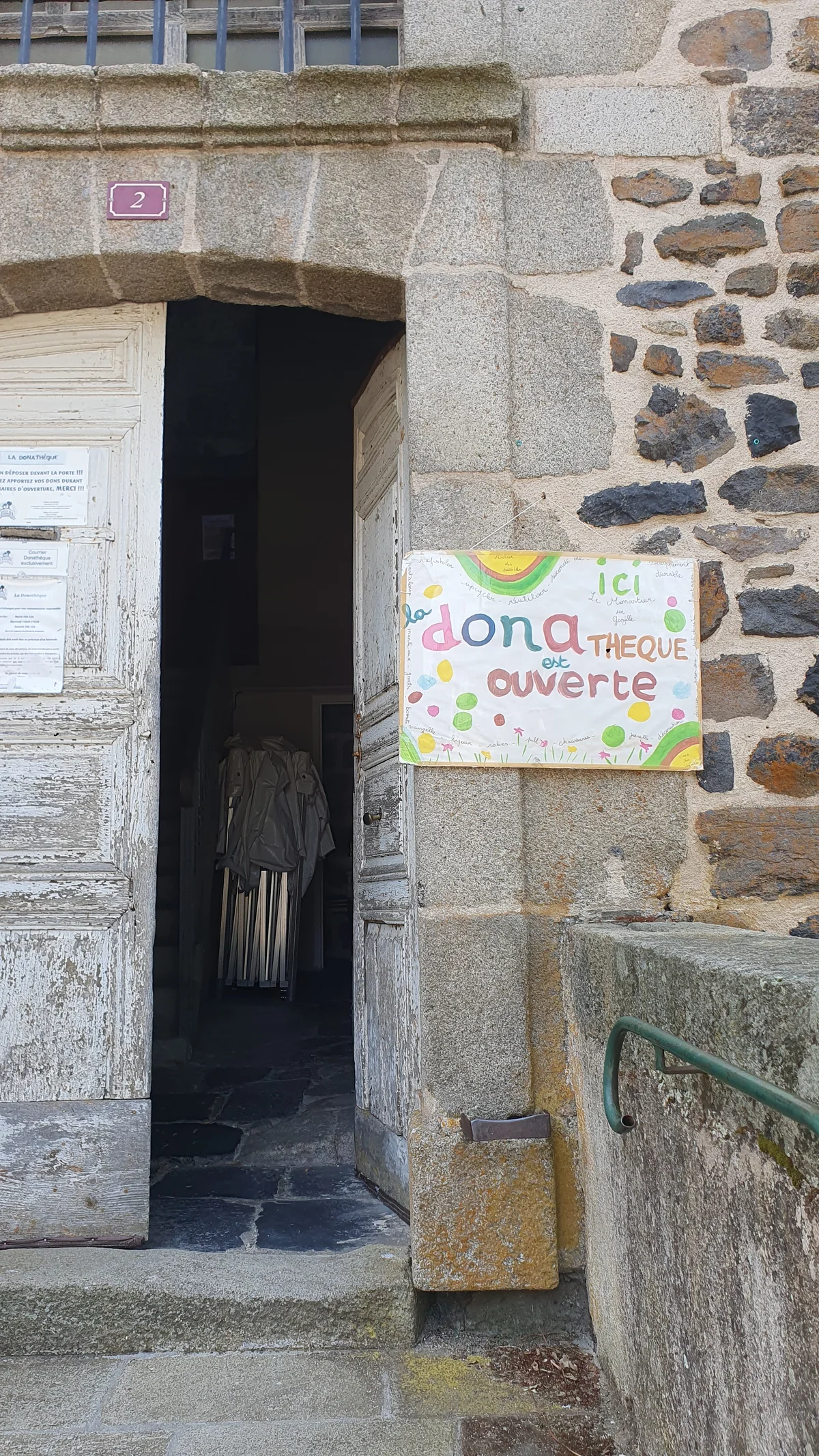L'entrée de la donathèque du Monastier, porte ancienne en bois et panneau peint à la main « la donathèque est ouverte »