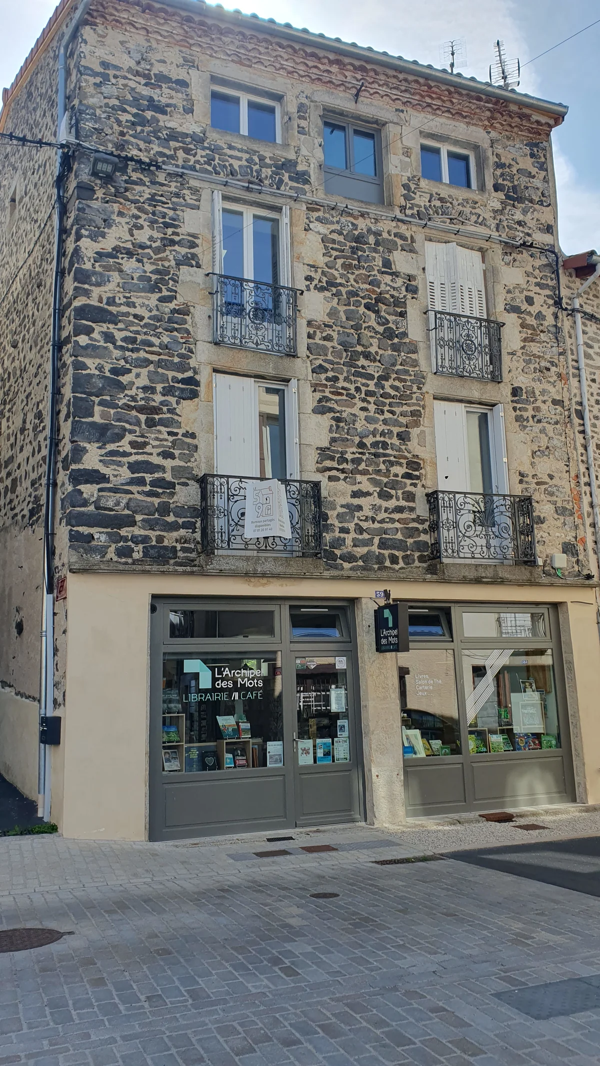 La façade en pierre du 59 au Monastier-sur-Gazeille, avec sa librairie-café au rez-de-chaussée et l'enseigne L'Archipel des Mots