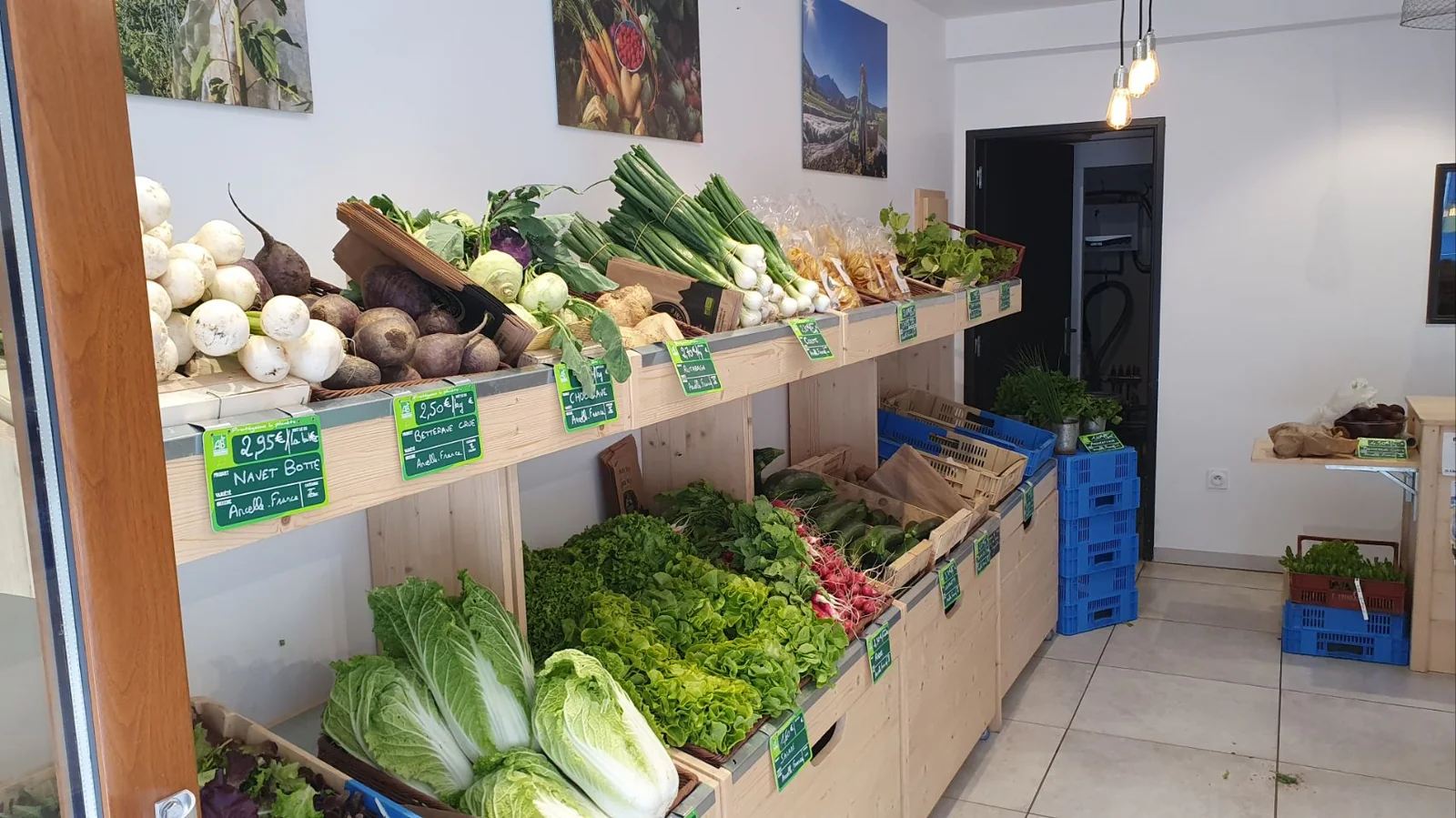 Étals de légumes bio dans le magasin : navets, betteraves, salades, blettes, le tout en cageots de bois avec ardoises de prix