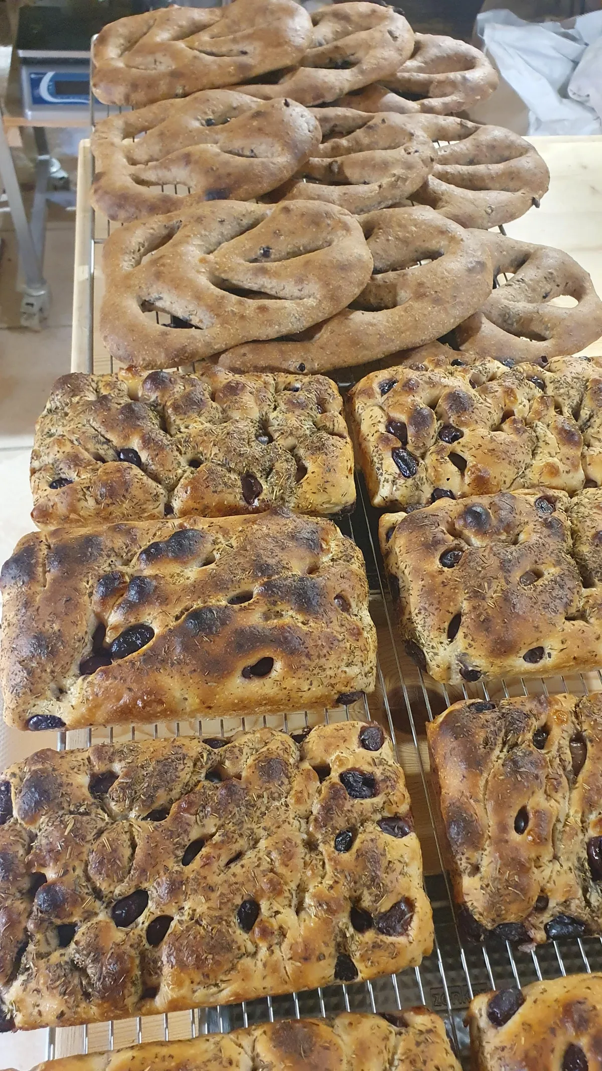 Des fougasses et des parts de focaccia aux olives empilées sur une grille